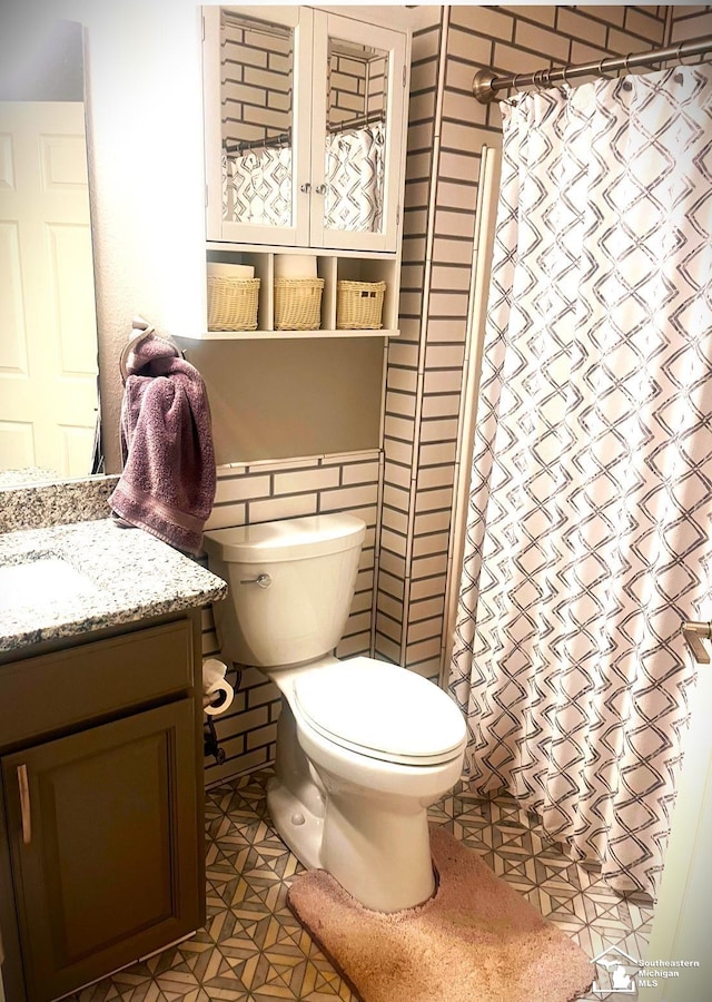 bathroom featuring tile patterned flooring, vanity, tile walls, and toilet