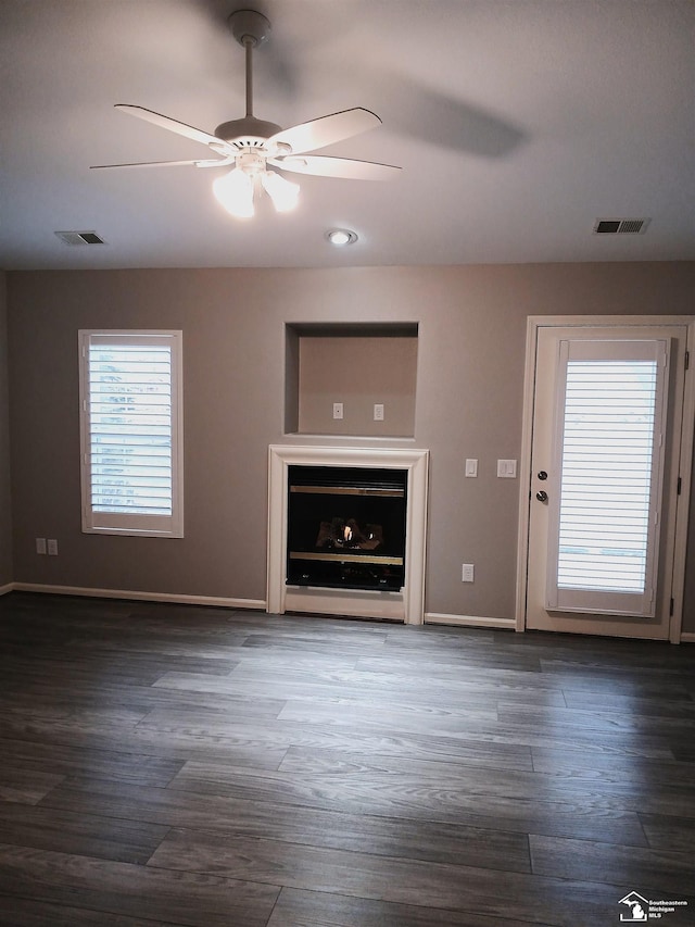 unfurnished living room with dark hardwood / wood-style flooring and ceiling fan