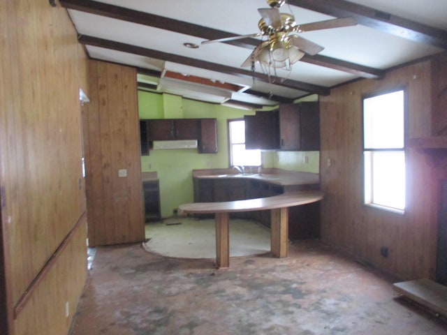 kitchen with vaulted ceiling with beams, ceiling fan, and wood walls