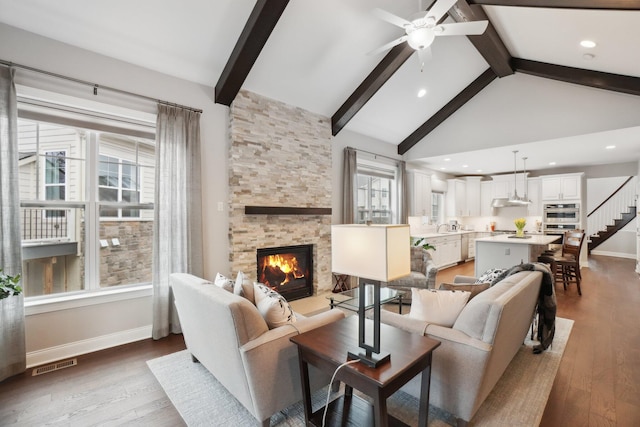 living room featuring a fireplace, beam ceiling, hardwood / wood-style flooring, and ceiling fan