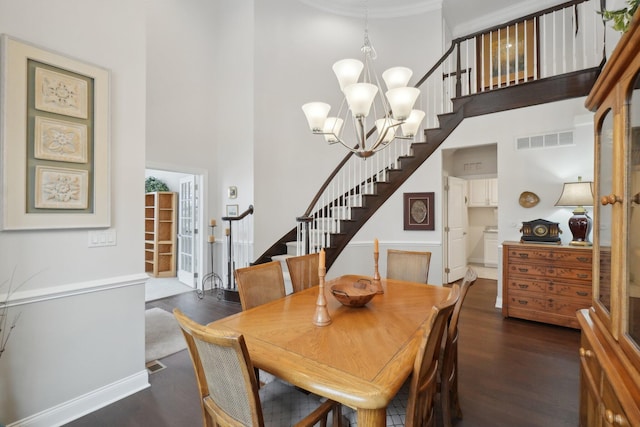 dining area featuring a high ceiling, dark hardwood / wood-style floors, and a notable chandelier