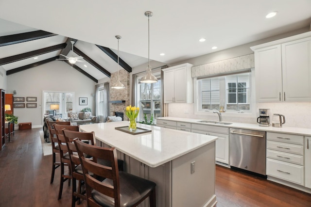 kitchen with stainless steel dishwasher, ceiling fan, sink, a center island, and white cabinetry