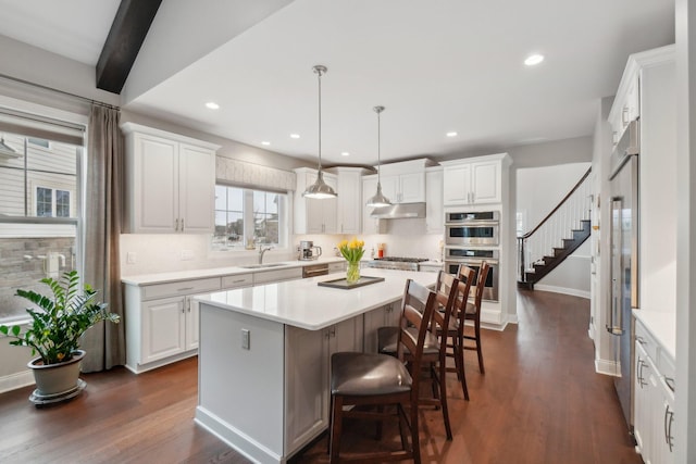 kitchen with beamed ceiling, a center island, white cabinetry, and stainless steel appliances