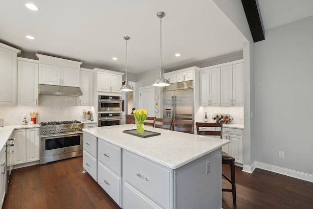 kitchen with a center island, high quality appliances, backsplash, white cabinets, and hanging light fixtures