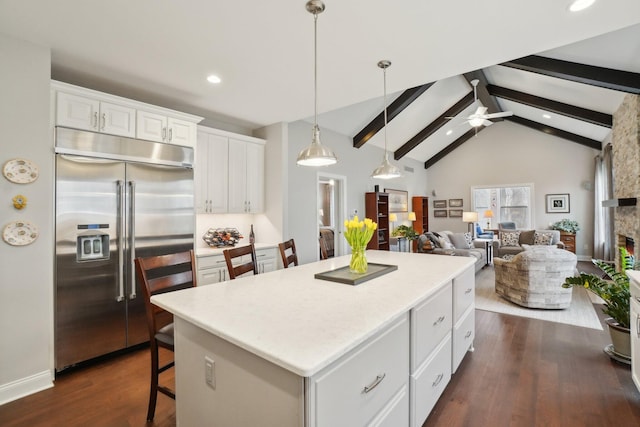 kitchen featuring a breakfast bar, white cabinetry, ceiling fan, a kitchen island, and stainless steel built in refrigerator