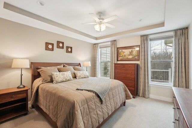 bedroom featuring ceiling fan, a raised ceiling, and light carpet