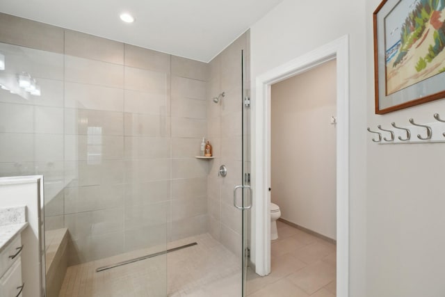 bathroom featuring tile patterned flooring, a tile shower, vanity, and toilet