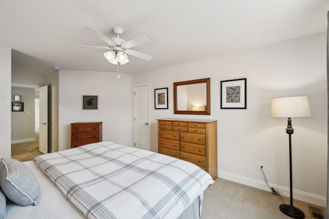 bedroom featuring light colored carpet, ceiling fan, and ensuite bathroom