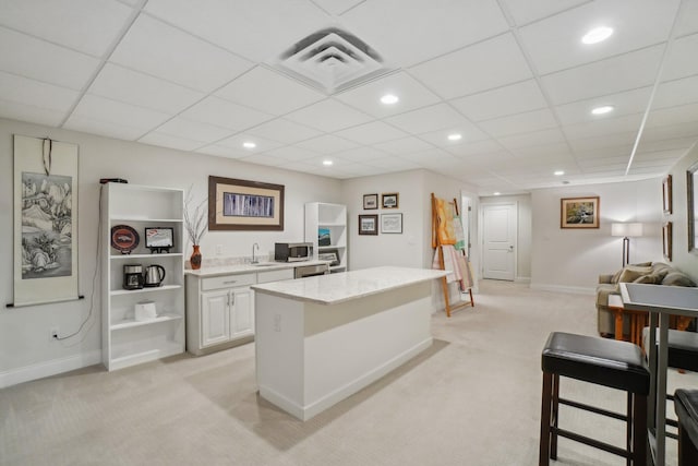 kitchen featuring white cabinets, a kitchen island, light colored carpet, and sink