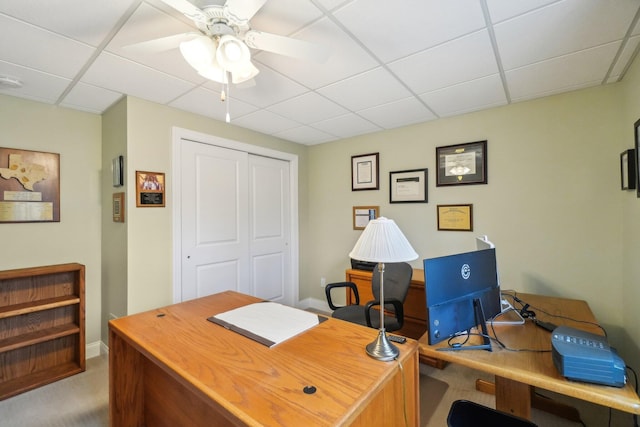 carpeted home office featuring a drop ceiling and ceiling fan