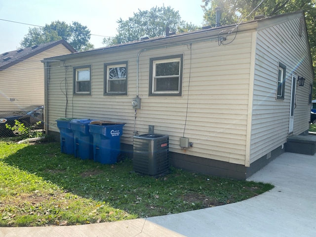 view of side of home featuring cooling unit and a lawn