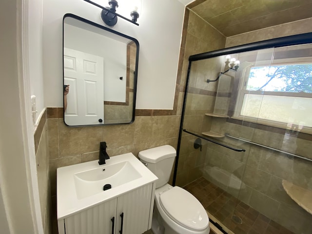 bathroom featuring vanity, toilet, tile walls, and a shower with shower door