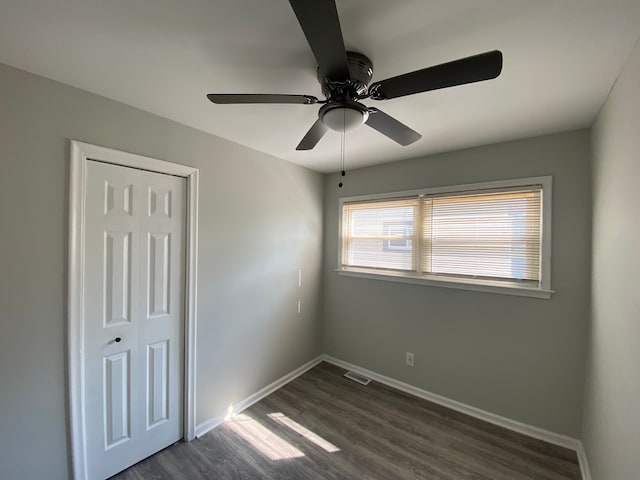 unfurnished bedroom with dark hardwood / wood-style flooring, a closet, and ceiling fan