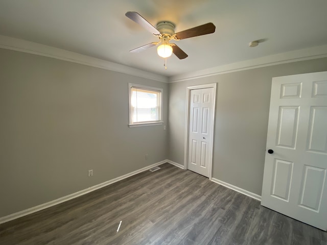 unfurnished bedroom featuring ceiling fan, dark hardwood / wood-style flooring, crown molding, and a closet