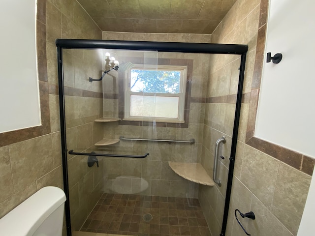 bathroom featuring toilet, an enclosed shower, and tile walls