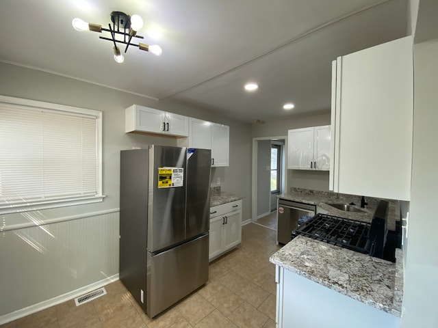 kitchen featuring light stone counters, white cabinetry, stainless steel appliances, and a chandelier