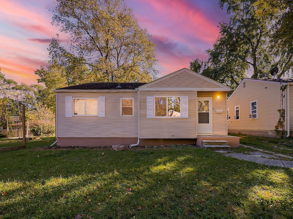 back house at dusk with a lawn