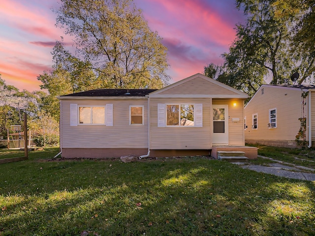 back house at dusk with a lawn