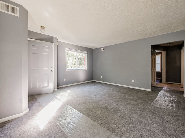 spare room featuring dark colored carpet and a textured ceiling