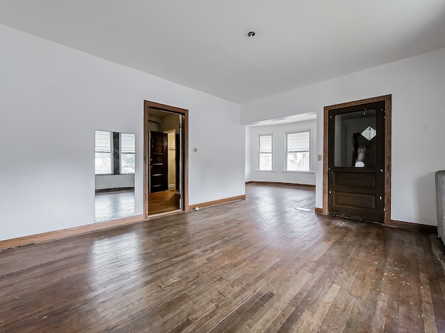 unfurnished living room with baseboards and dark wood-style flooring