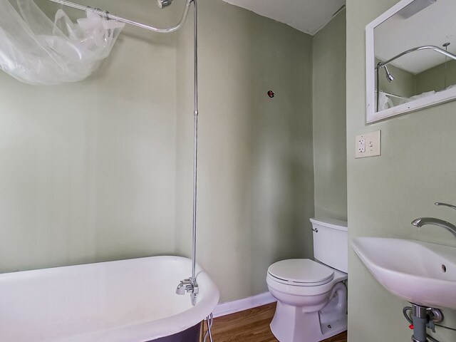 bathroom with hardwood / wood-style floors, sink, a bath, and toilet