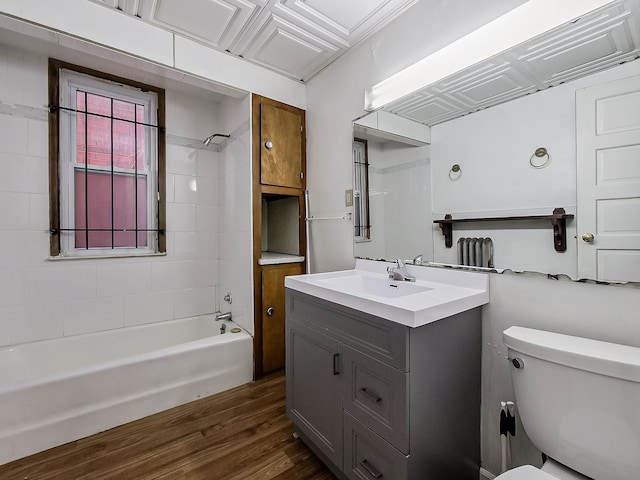 full bathroom featuring vanity, wood-type flooring, tiled shower / bath combo, and toilet