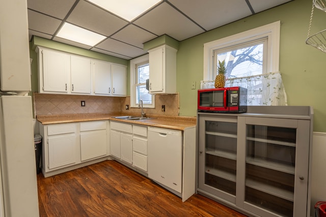 kitchen with tasteful backsplash, a paneled ceiling, dishwasher, white cabinets, and sink