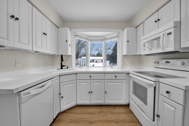 kitchen featuring white cabinetry, sink, light hardwood / wood-style floors, and white appliances