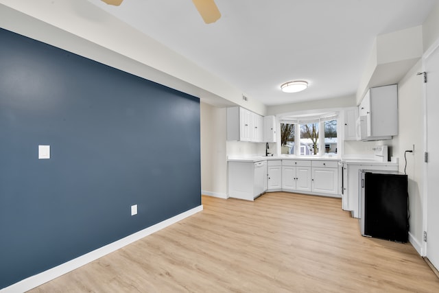 kitchen with white cabinetry, ceiling fan, sink, light hardwood / wood-style flooring, and white appliances