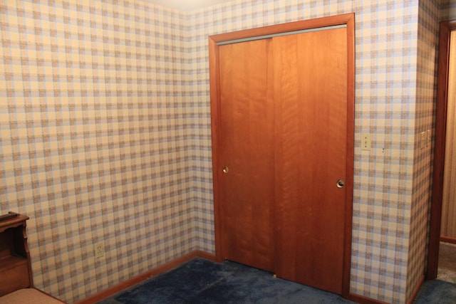 unfurnished bedroom featuring dark carpet and a closet