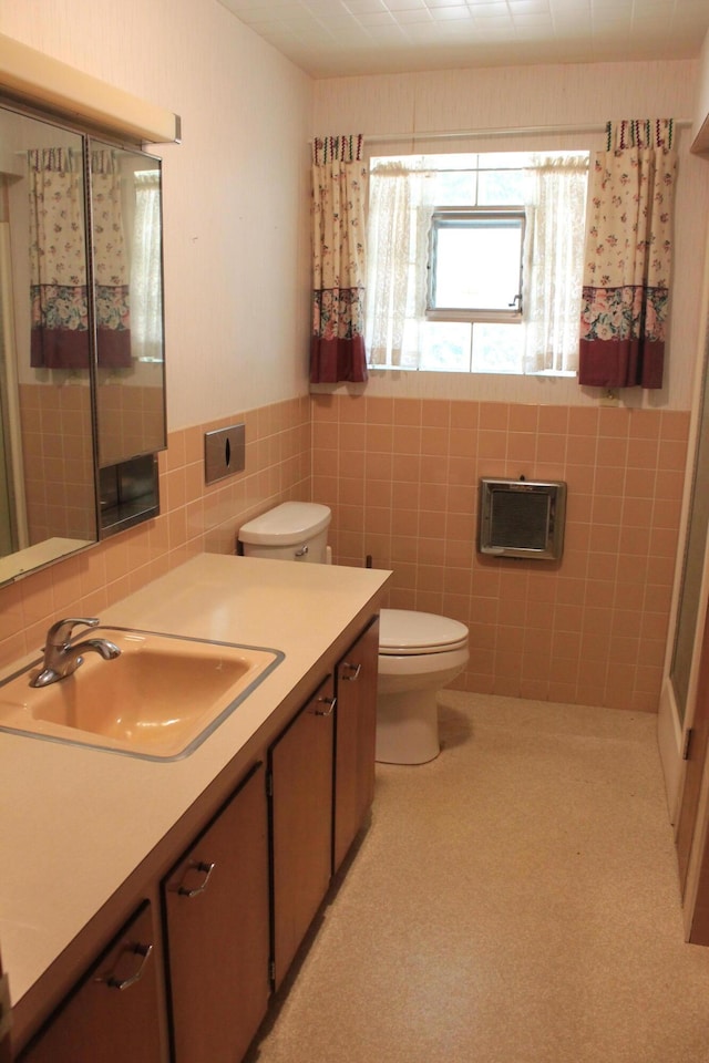 bathroom with vanity, toilet, and tile walls