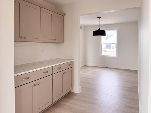 kitchen featuring baseboards, light countertops, gray cabinets, light wood-style flooring, and hanging light fixtures