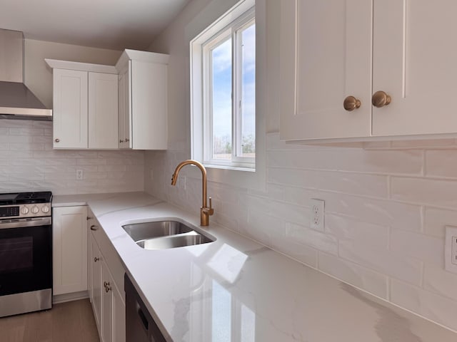 kitchen featuring wall chimney range hood, light stone counters, a sink, white cabinetry, and stainless steel electric stove