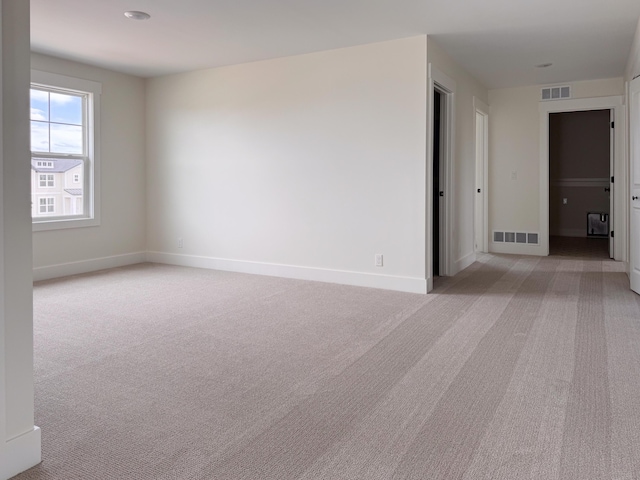 unfurnished room with baseboards, light colored carpet, and visible vents