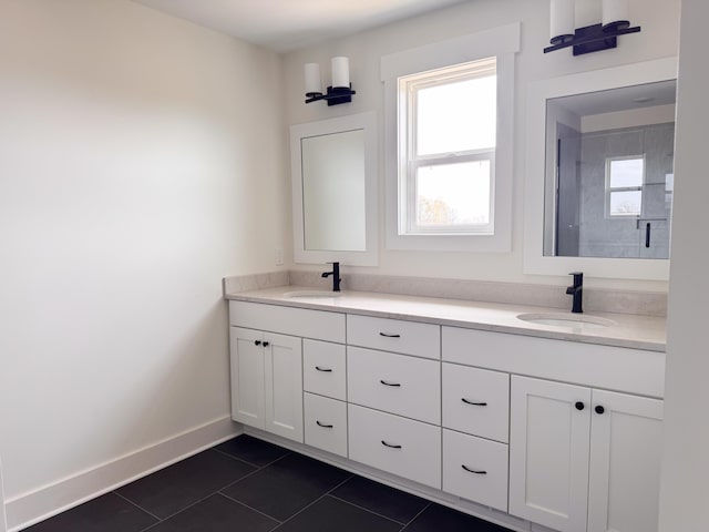bathroom featuring baseboards, double vanity, tile patterned floors, and a sink