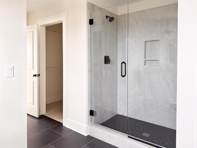 bathroom featuring baseboards, tile patterned flooring, a stall shower, and a spacious closet