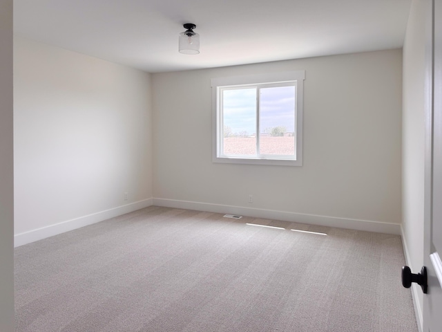 empty room featuring baseboards, light carpet, and visible vents