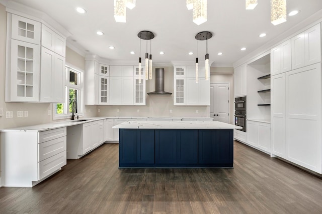 kitchen featuring a center island, white cabinets, and wall chimney range hood