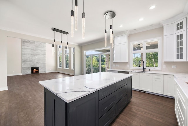 kitchen with a high end fireplace, dark wood-type flooring, pendant lighting, white cabinets, and a center island