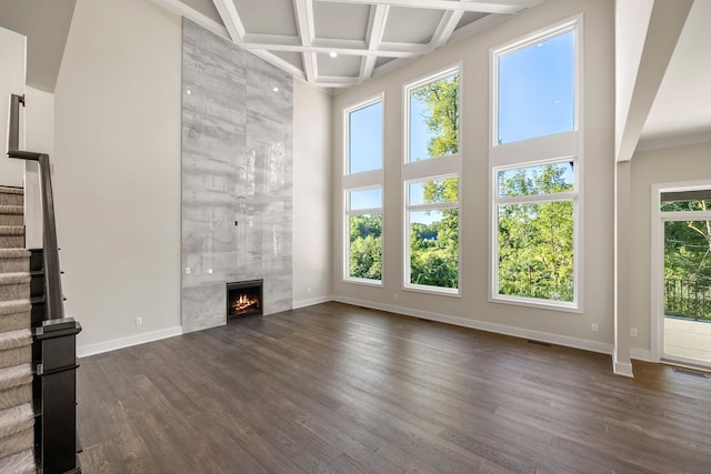 unfurnished living room featuring a fireplace, dark hardwood / wood-style flooring, and a healthy amount of sunlight