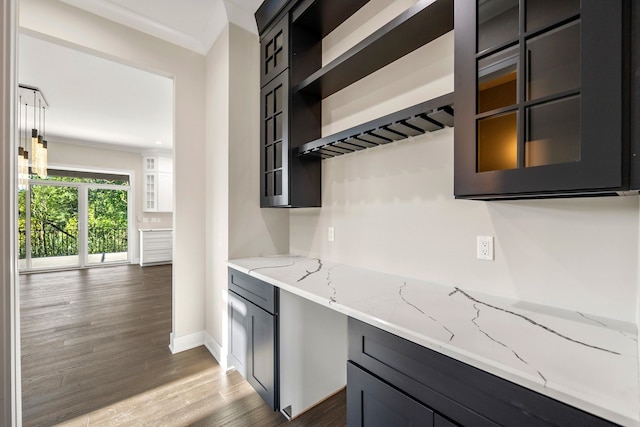 kitchen with dark hardwood / wood-style floors, light stone countertops, and ornamental molding