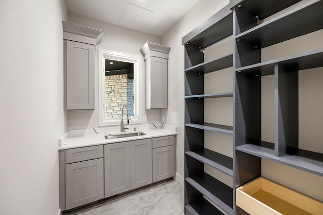 interior space featuring gray cabinets, light stone counters, and sink