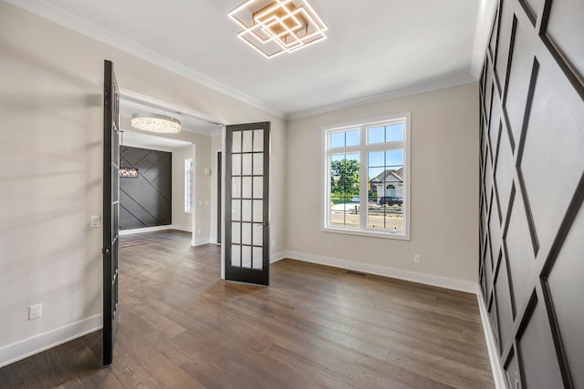 empty room with a chandelier, dark hardwood / wood-style flooring, ornamental molding, and french doors