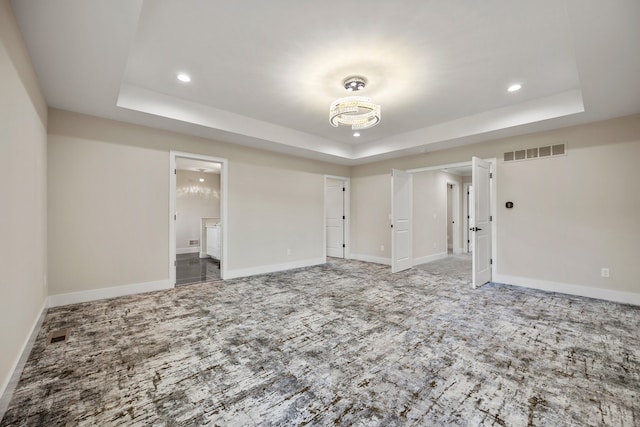 carpeted empty room with a tray ceiling