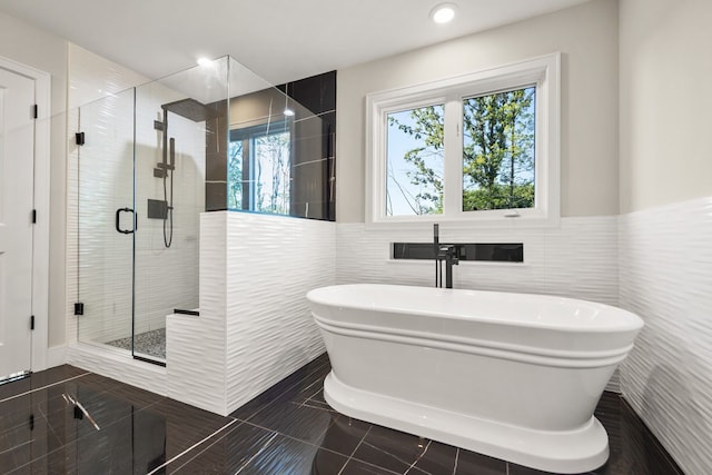 bathroom featuring tile patterned floors, shower with separate bathtub, sink, and tile walls