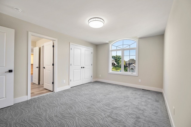 unfurnished bedroom featuring connected bathroom and light colored carpet