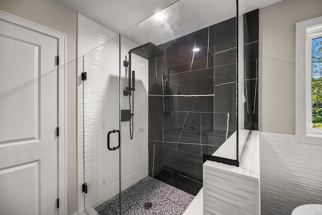 bathroom with a shower with door and tile walls