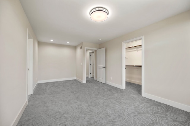 unfurnished bedroom featuring a walk in closet, light carpet, and a closet