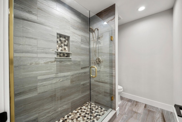 bathroom featuring hardwood / wood-style flooring, toilet, and a shower with shower door