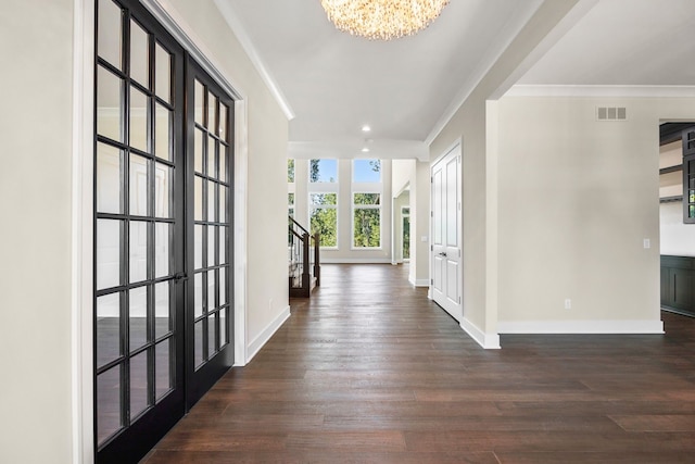 corridor featuring french doors, dark hardwood / wood-style flooring, an inviting chandelier, and ornamental molding